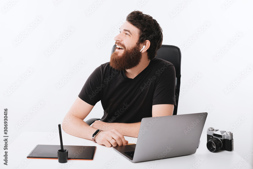 Happy bearded man is looking away near his desk. Happy bearded man is looking away near his desk.