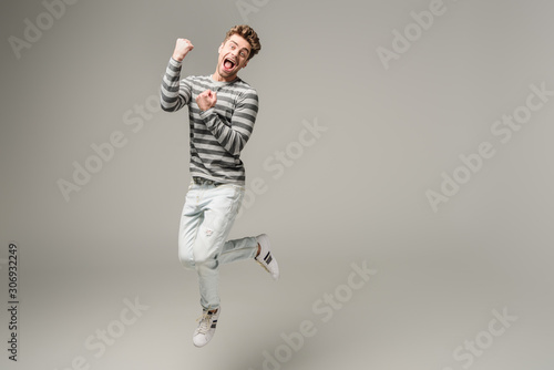 excited screaming man jumping and cheering on grey