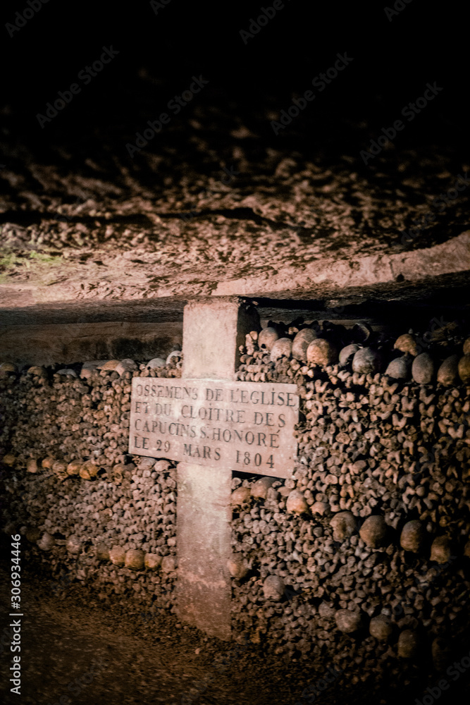 Skulls and bones in Paris catacombs, France. Old broken skull placed on the bones. Underground cemetery.