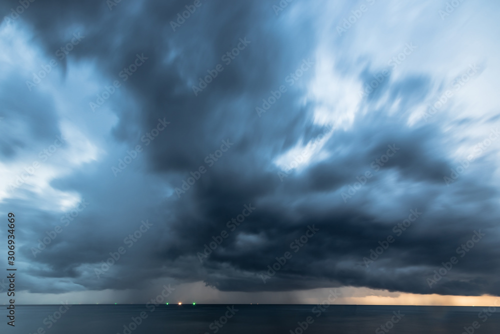 Long exposure of storm coming lead scary cloud in dark mode with strong wind on the sky over the ocean