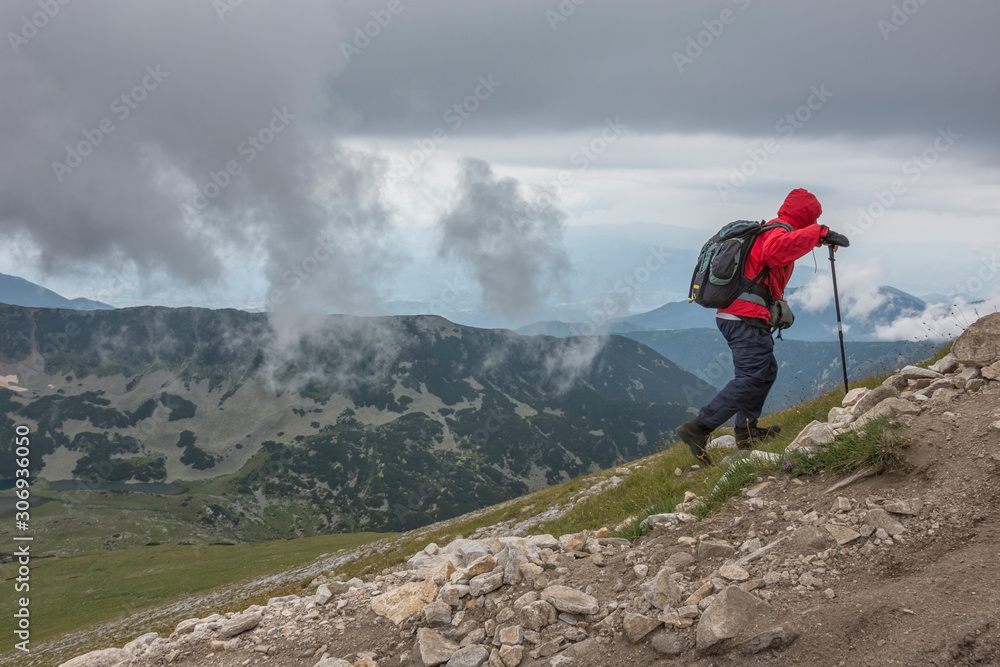 Tourist, hiker on his way to the top of the maintain in cloudy weather. National park Pirin. Selective focus. Healthy lifestyle concept, be active, adventure.