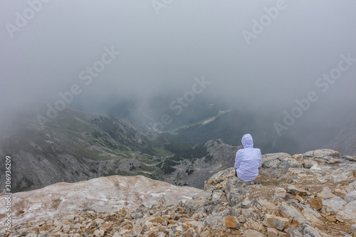 Hiker sitting at the edge of mountain in foggy weather. National park Pirin. Selective focus. Healthy lifestyle concept, be active, adventure. photo