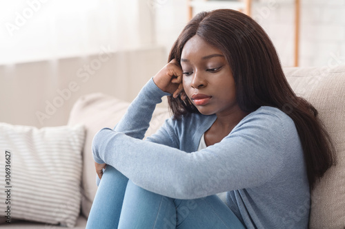 Upset black girl sitting on couch with thoughtful face expression Free Download Upset black girl sitting on couch with thoughtful face expression - GFXLoad