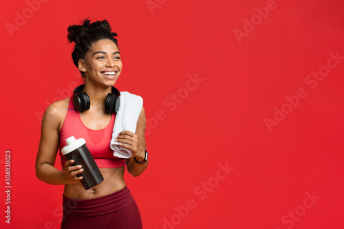 Cheerful fitness girl drinking protein during exercising