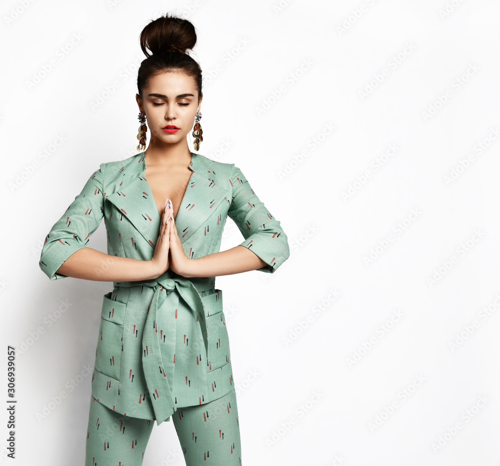 Young fashionable beautiful girl blogger trying on an expensive designer stylish green office suit on a white Young fashionable beautiful girl blogger trying on an expensive designer stylish green office suit on a white