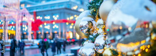Urban street with Christmas decorations. Xmas lights and people walking around on the street. Blurred background. New Year Celebration concept.