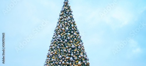 Decorated outdoor Christmas Tree with beautiful festive arrangement of fresh spruce with balls. Christmas morning. Festive street decor in winter holidays.