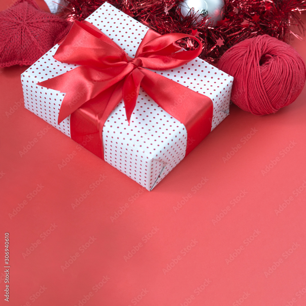 Gift box with red bow, tinsel, and knitted stars close-up. Gift concept for needlewoman Gift box with red bow, tinsel, and knitted stars close-up. Gift concept for needlewoman