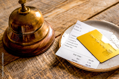 restaurant bill, card and waiter ring on wooden table background photo