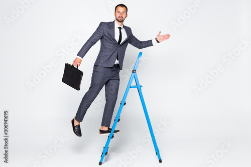 Full length portrait of a businessman with briefcase climbing a ladder isolated on white background