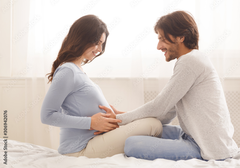Man touching belly of his pregnant wife in bed at home Man touching belly of his pregnant wife in bed at home