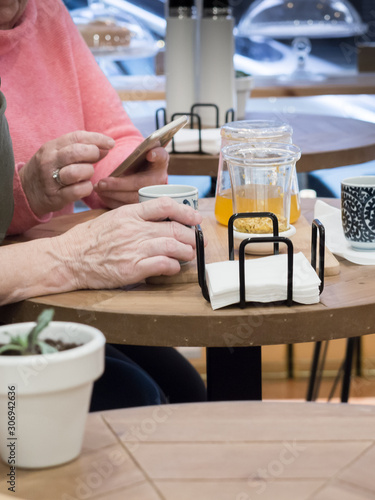 manos personas mayores en mesa cafeteria con movil