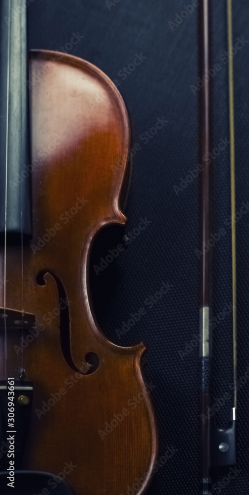 The abstract art design background of wooden violin put on background,show half front side of string instrument beside bow,on black canvas background The abstract art design background of wooden violin put on background,show half front side of string instrument beside bow,on black canvas background