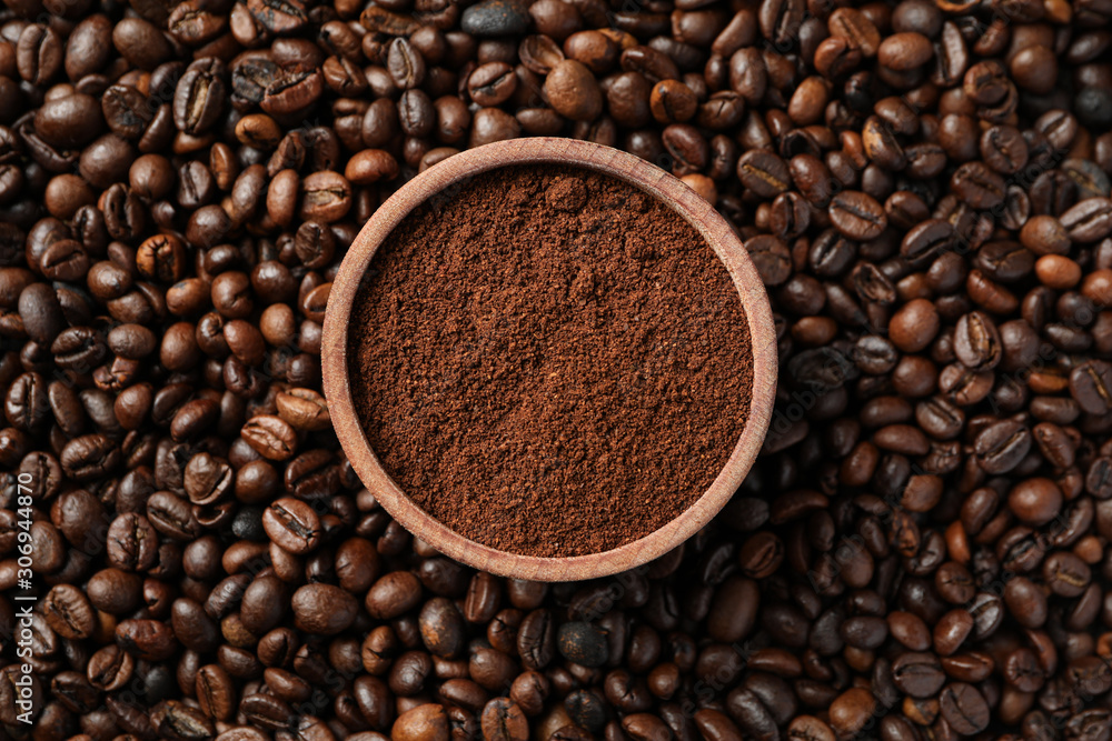 Textured background of coffee beans with bowl of powder, close up Textured background of coffee beans with bowl of powder, close up