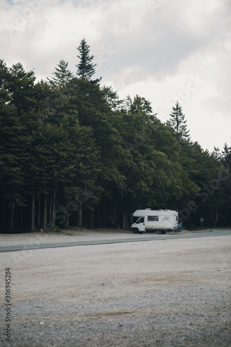 Small travel vehicle camping van parked by the roadside next to the forest. Tourism vacation and travel. Camper van and wild landscape