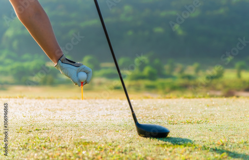 Female golfer hand holding golf ball and golf tee
