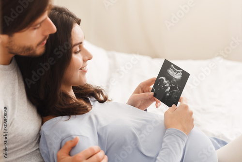 Happy pregnant woman and her husband looking at sonogram picture photo