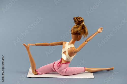 plastic doll in yoga pose on a gray background , healthy lifestyle concept