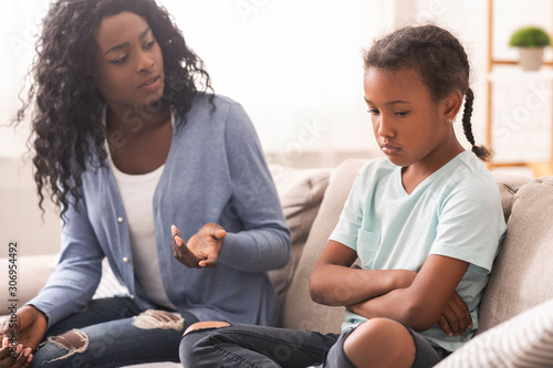 Disappointed black mother looking at her little daughter with reproach photo