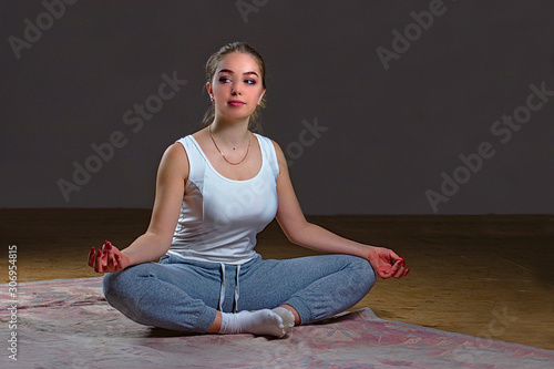Girl practices yoga indoors on a rug on the floor