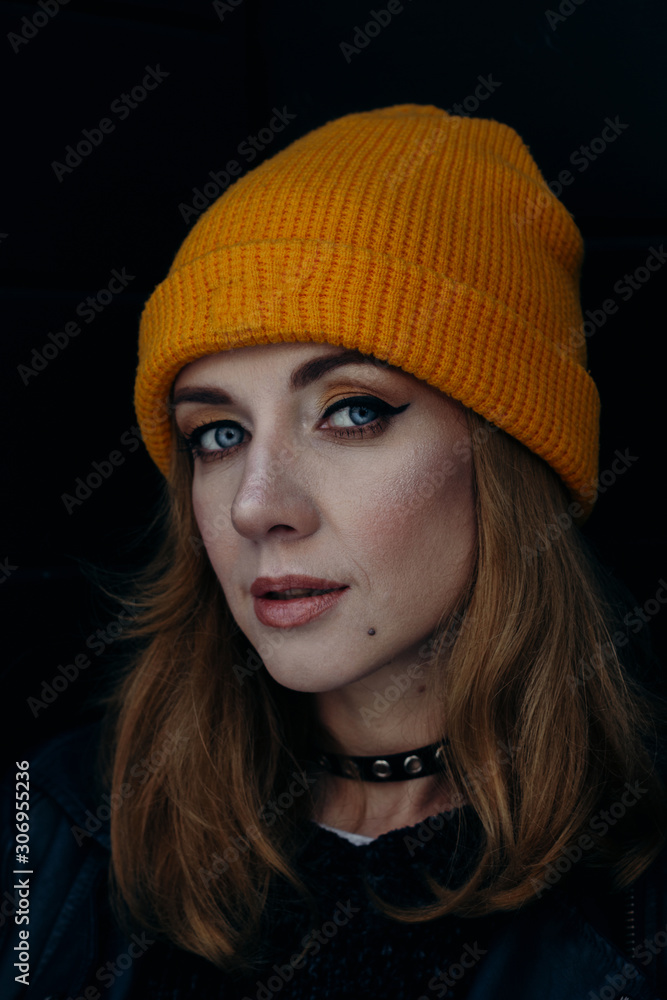 head shot of a confident beautiful caucasian woman in a yellow hat on a black background head shot of a confident beautiful caucasian woman in a yellow hat on a black background