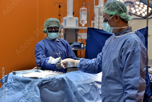 Team surgeon at work in operating room. Surgical light in the operating room. Preparation for the beginning of surgical operation with a cut. The surgeon is performing surgery on the patient.