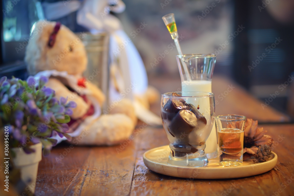 Choosing Focus: An ice heart latte is on a plate, try to place on a table, counter, and there is a teddy bear nearby in a warm atmosphere