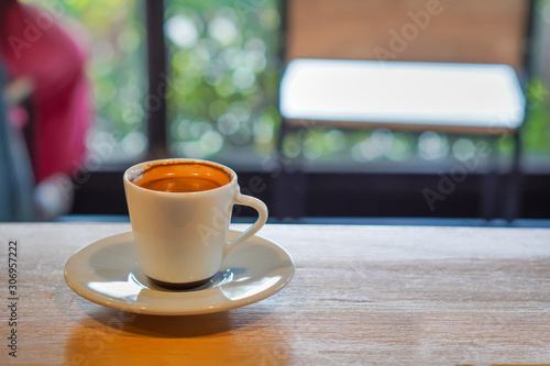 Focus selection: Coffee in a white cup, placed on a counter table in a warm atmosphere, can see the atmosphere outside the shop