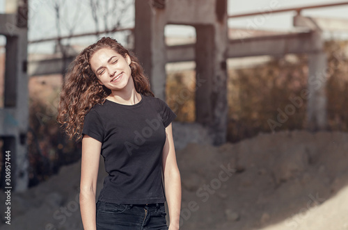 Attractive smiling girl standing at industrial area on the background of an abandoned building.