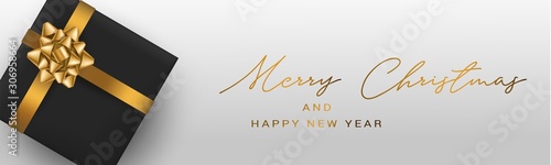 Merry Christmas and a Happy New Year banner or header. Simple luxurious design with golden ribbon and bow, black gift box. Winter holidays concept. Hand written lettering. Vector illustration.