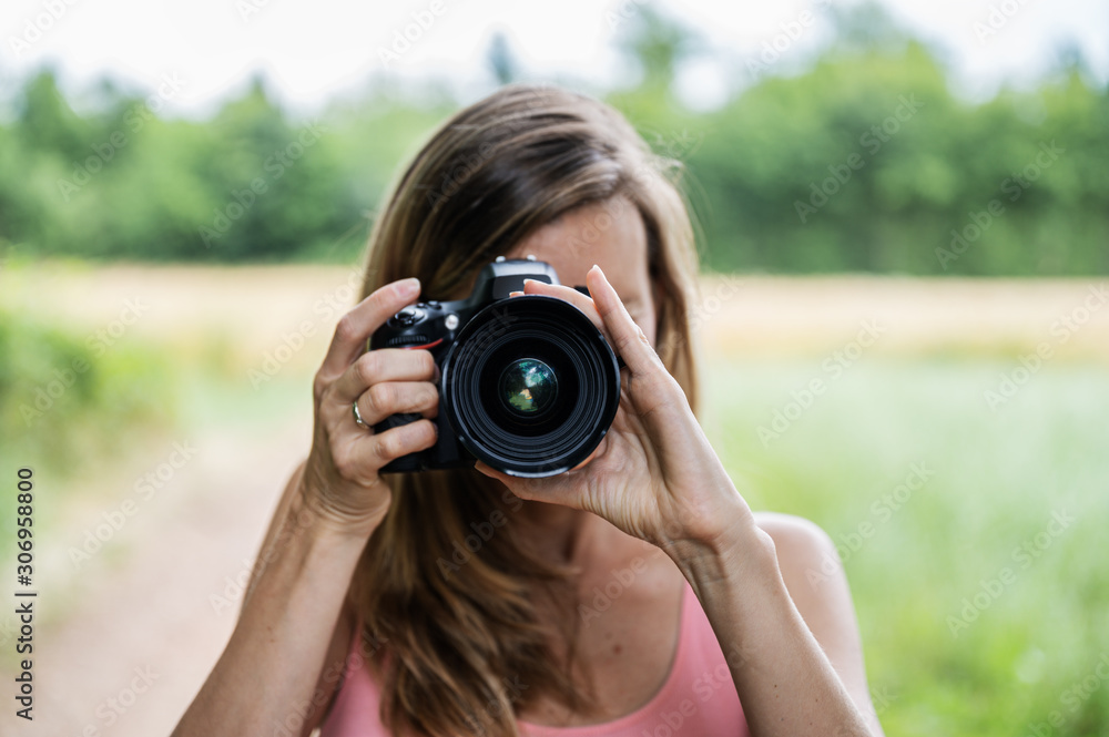 Young female photographer taking a photo directly at you Young female photographer taking a photo directly at you