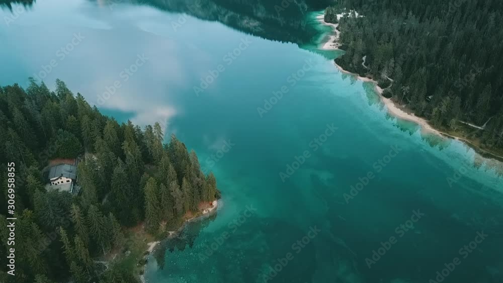 Aerial: Tracking shot over the glassy surface of a mountain lake, mirroring a blurry sky with a few clouds Aerial: Tracking shot over the glassy surface of a mountain lake, mirroring a blurry sky with a few clouds