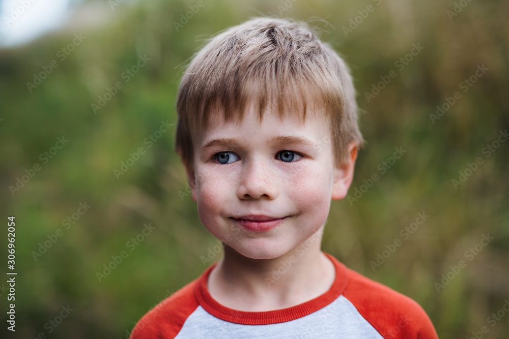 A portrait of school boy standing in nature, looking at camera. A portrait of school boy standing in nature, looking at camera.