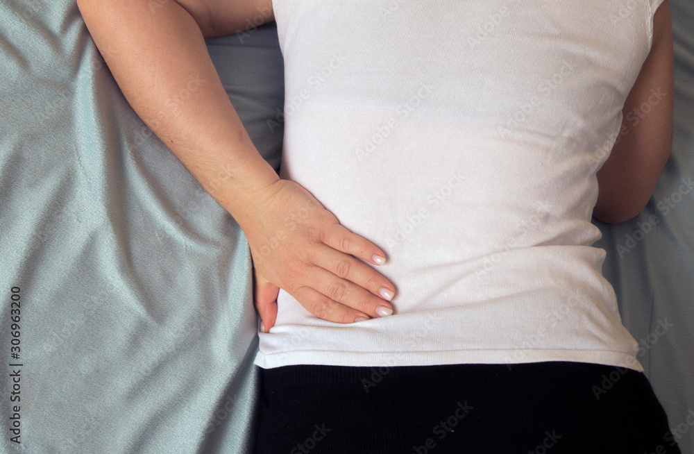 woman holds her hand on her back. backache woman holds her hand on her back. backache