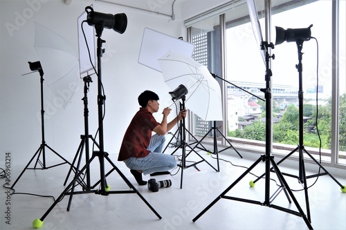 Photographer working with equipment lighting system camera portrait professional studio set up position