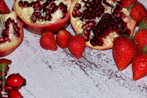 tasty summer fruits on a wooden table. strawberry, pomegranate