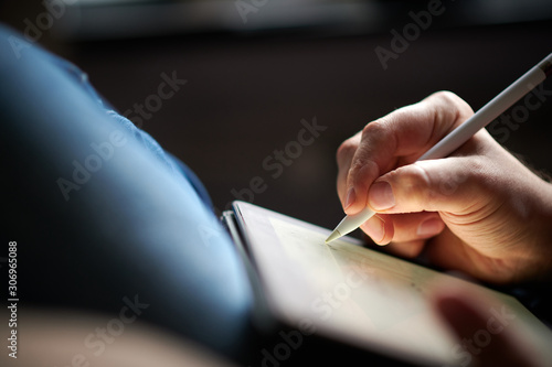 Hand schreibt mit einem Eingabestift auf einem Tablet