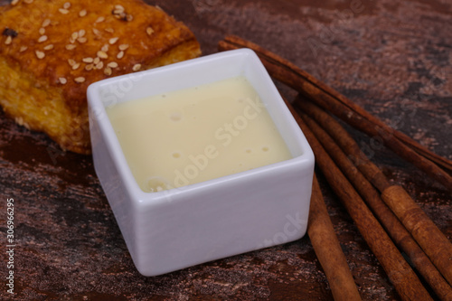 Condenced milk in the bowl with sinnamon and pastry photo