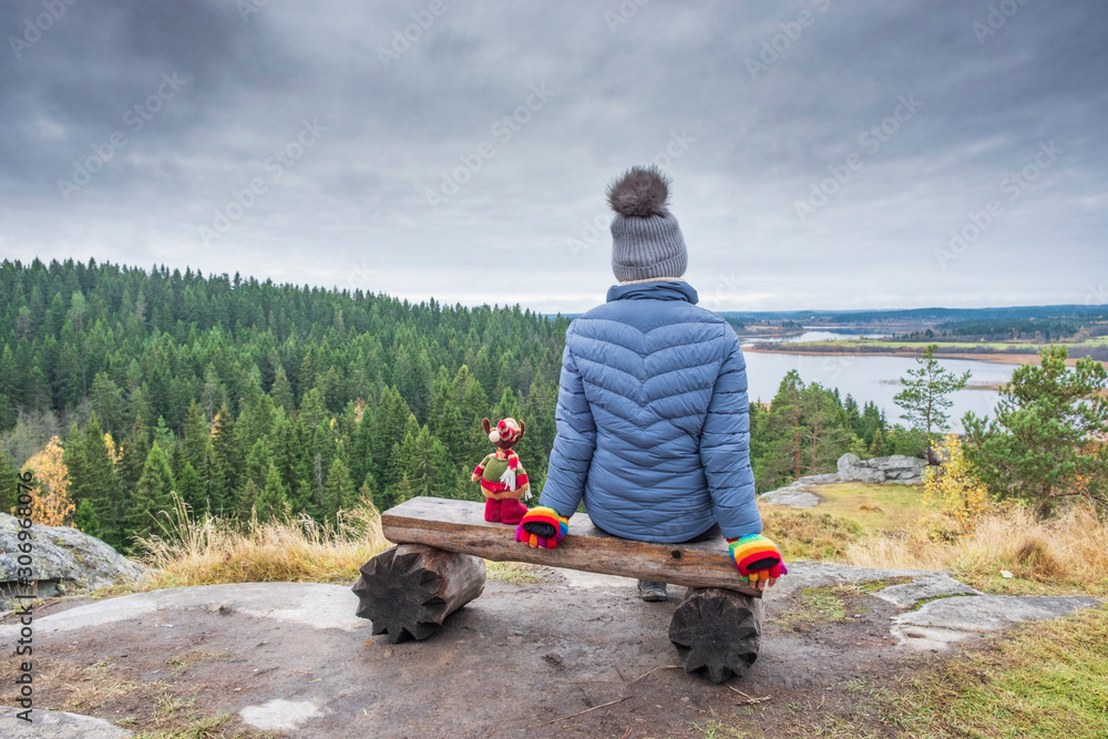 girl with toy elk  admires the view of autumn Karelia from the height of the hillfort on Mount Paaso near the town of Sortavala