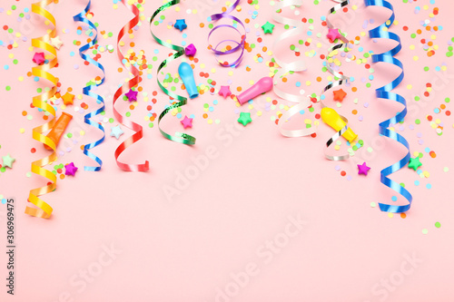 Colorful ribbons with paper stars and confetti on pink background