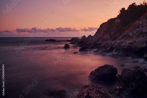 Long exposure photography of the sea waves splashing near to the clif when the sun is going down