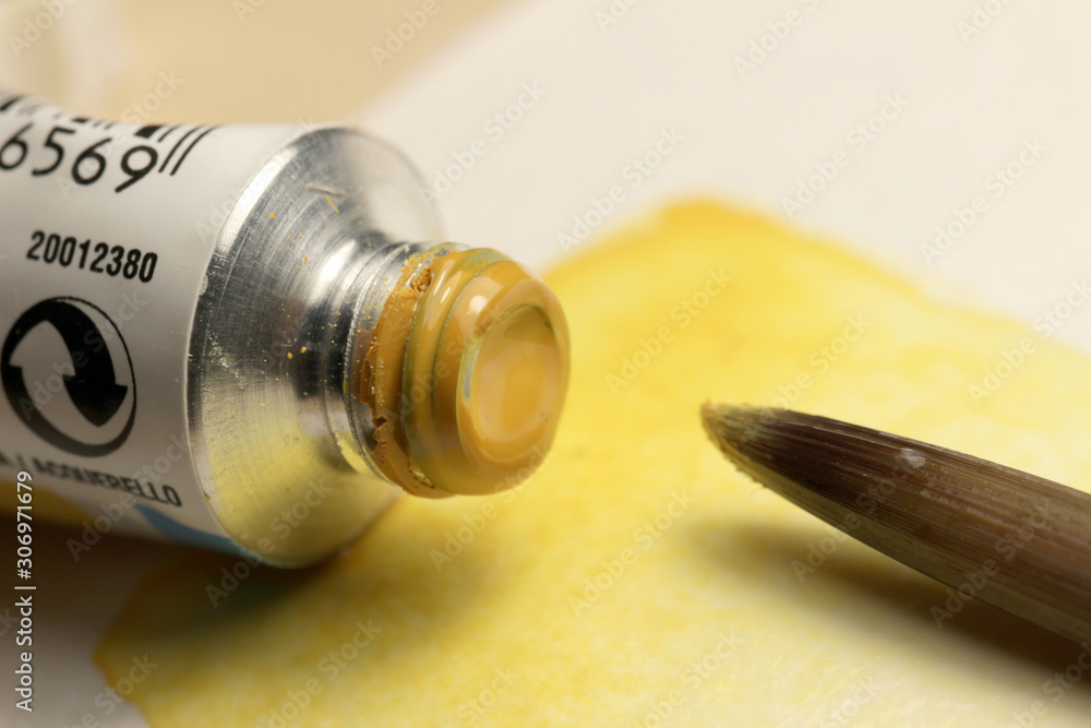 Yellow Watercolor paint tube and a brush on hand painted background Yellow Watercolor paint tube and a brush on hand painted background