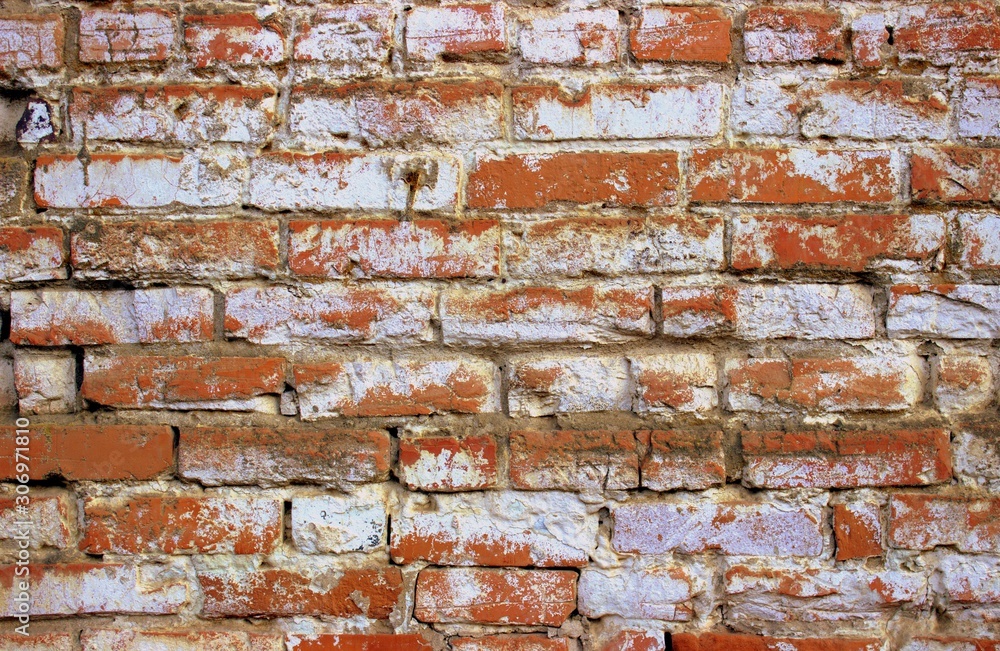 Fototapeta premium A shot of an old orange brickwork painted over with white paint. Vintage photo of the wall of an old building