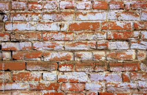  A shot of an old orange brickwork painted over with white paint. Vintage photo of the wall of an old building