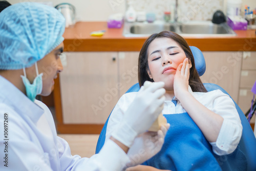 Asian dentist and the patient are preparing to treat carious teeth in the dental clinic