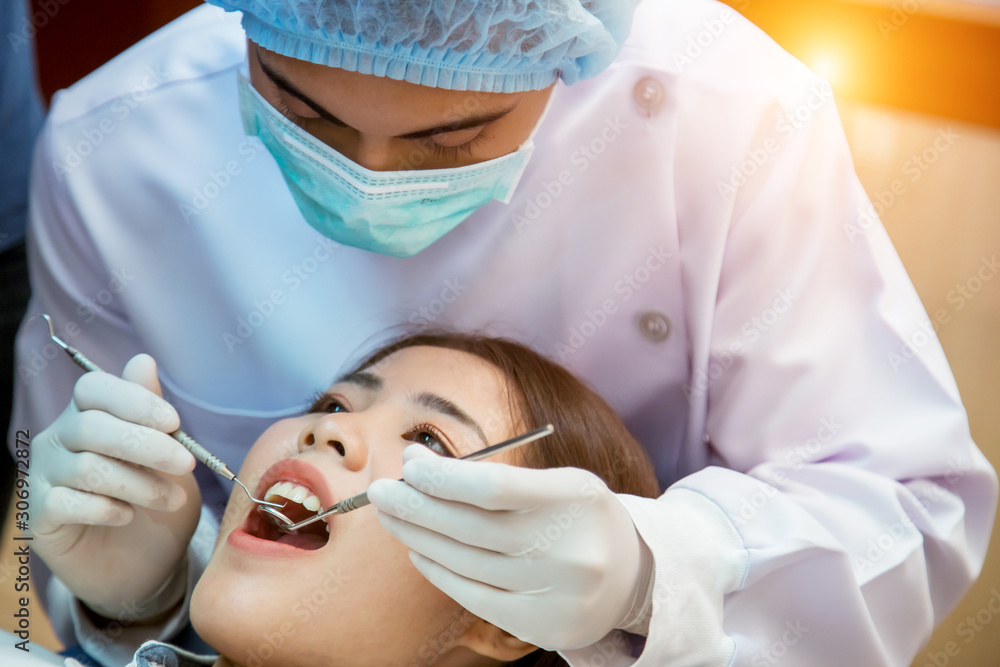 Young man dentist who treats teeth of young woman patient.