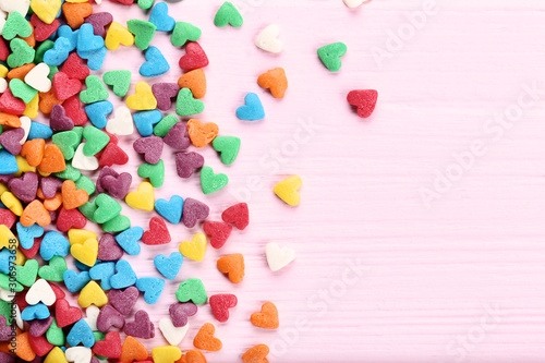 Colorful heart shaped sprinkles on pink wooden table