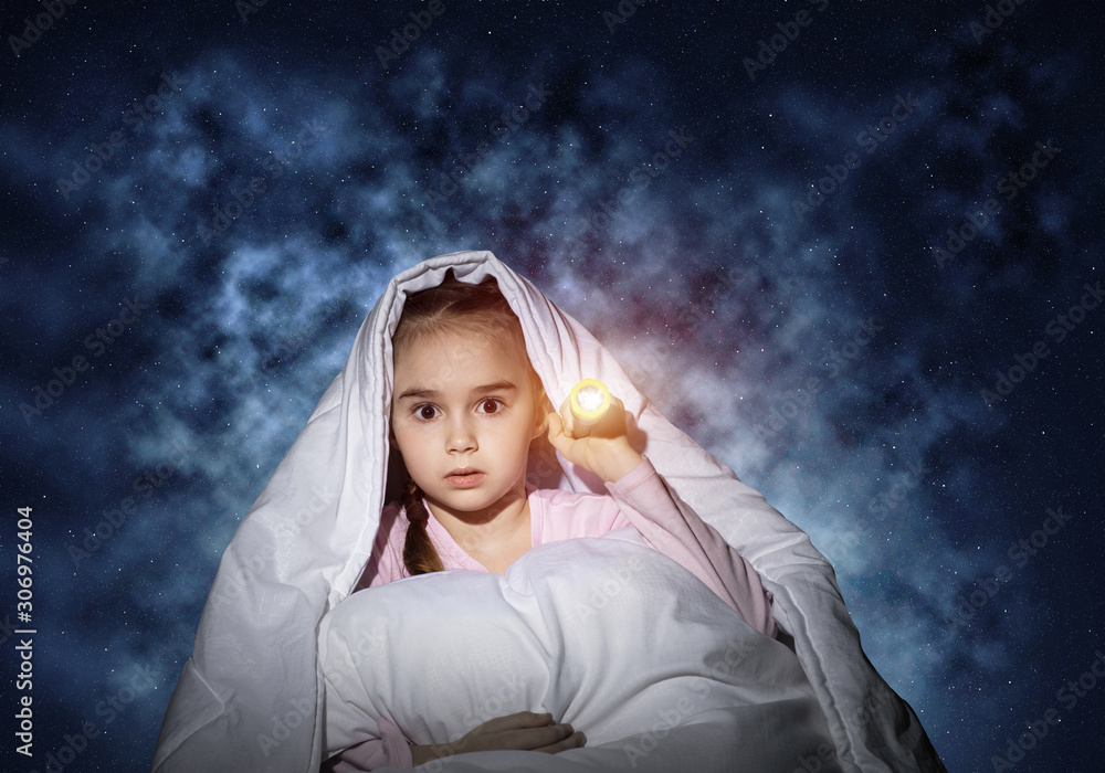 Frightened girl with flashlight under blanket
