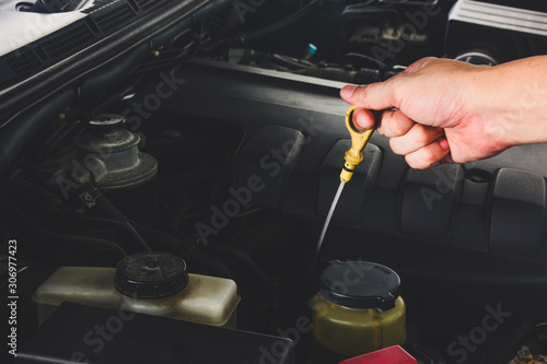 close up auto mechanic's hand checks the level of engine oil in a car engine during maintenance © iamtui7