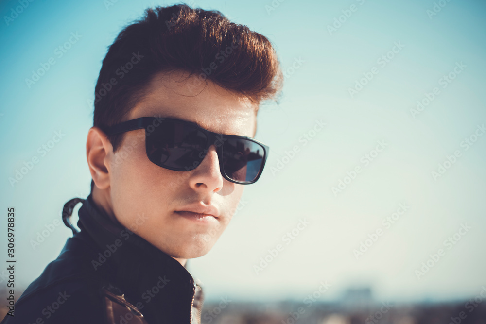 Young attractive man posing in front of camera in a dark brown jacket on the roof of a residential building Young attractive man posing in front of camera in a dark brown jacket on the roof of a residential building